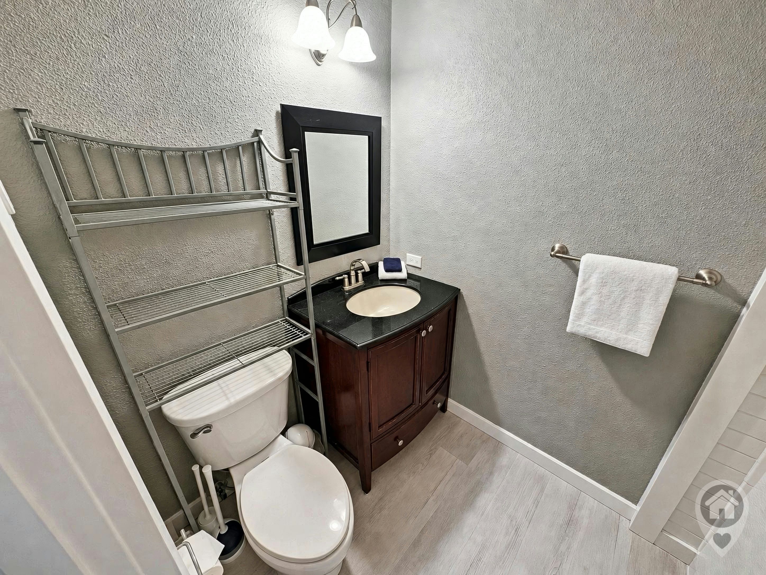Une salle de bain équipée de toilettes, d’un lavabo, d’un meuble-lavabo et d’étagères.