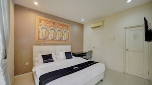 A hotel room with a bed, a desk, an air conditioning unit, and a door. - Collection O near Mall Ciputra (Pekanbaru)