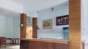 A reception desk with a wooden finish, a framed picture, and a sign indicating the hotel is part of the Malang development. - Collection O near Mall Ciputra (Pekanbaru)