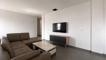 Ein modernes Wohnzimmer mit einem Ecksofa, einem Couchtisch, einem an der Wand montierten Fernseher und einer Holzkommode.