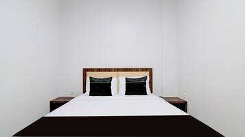 A standard hotel room with a single bed, two bedside tables, and a plain wall.