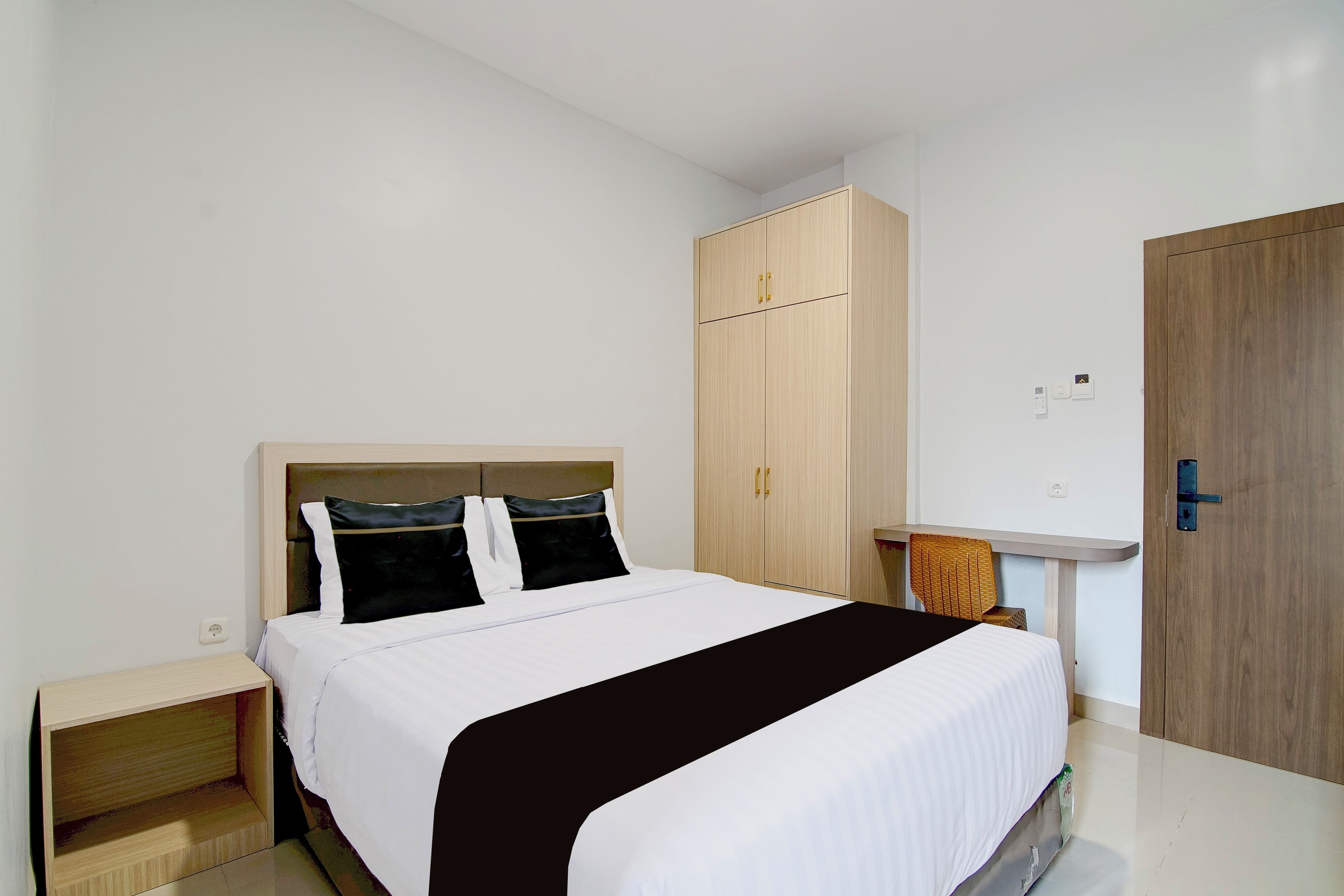 Una habitación de hotel con cama, armario, mesita de noche y puerta.