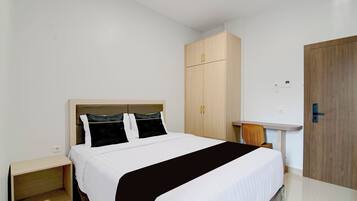 Una habitación de hotel con cama, armario, mesita de noche y puerta.