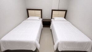 Habitació amb dos llits individuals, cadascun amb un capçal de fusta i roba de llit blanca.