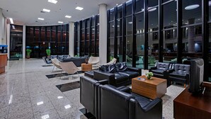 Eine moderne Lobby mit einer gebogenen Glaswand, Ledersitzgelegenheiten und einem Empfangstresen.