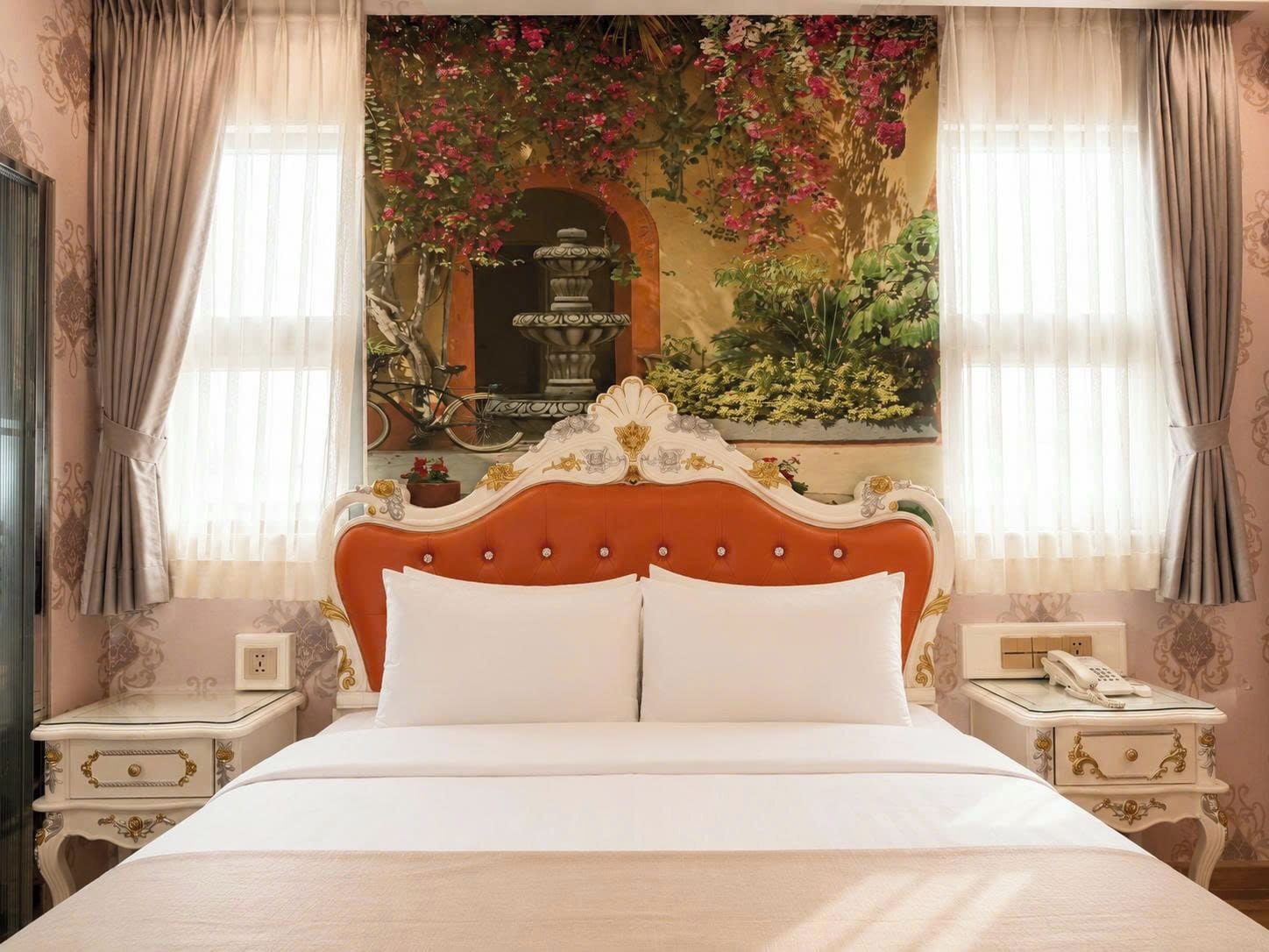 Una cama con cabecera blanca y dos almohadas, flanqueada por dos mesitas de noche con lámparas y un teléfono.
