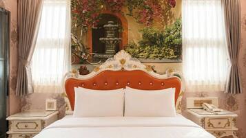 Una cama con cabecera blanca y dos almohadas, flanqueada por dos mesitas de noche con lámparas y un teléfono.