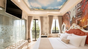 Un dormitorio lujoso con una cama grande, un techo ornamentado y un balcón con vistas.