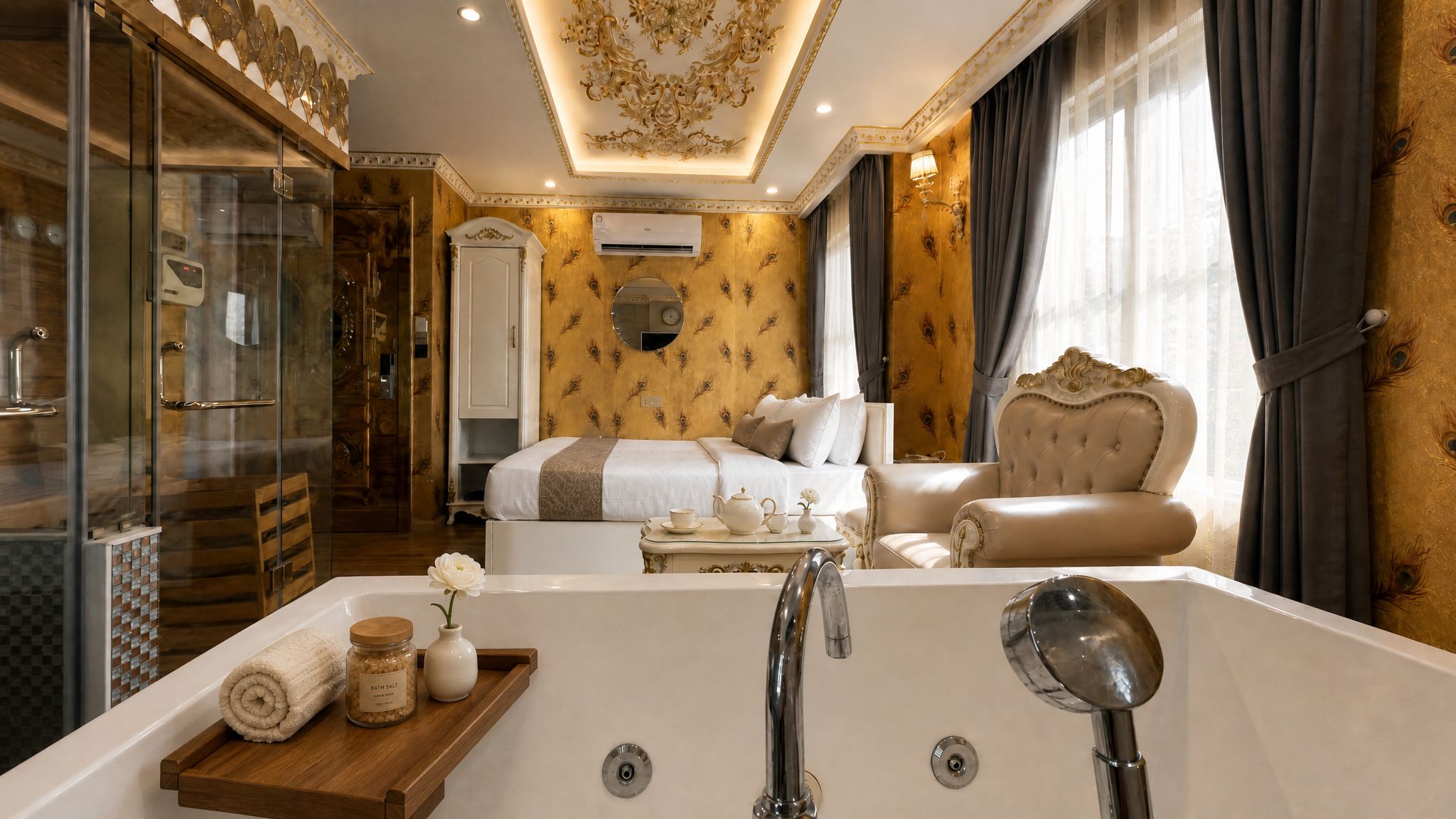 A luxurious hotel room with a large bathtub, a separate sitting area with a sofa and armchair, a walk-in closet, and a bedroom with a bed and a dresser.