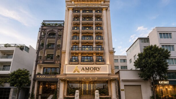 Un hotel de varios pisos con una entrada destacada, una estatua en la base y balcones con barandillas ornamentales.