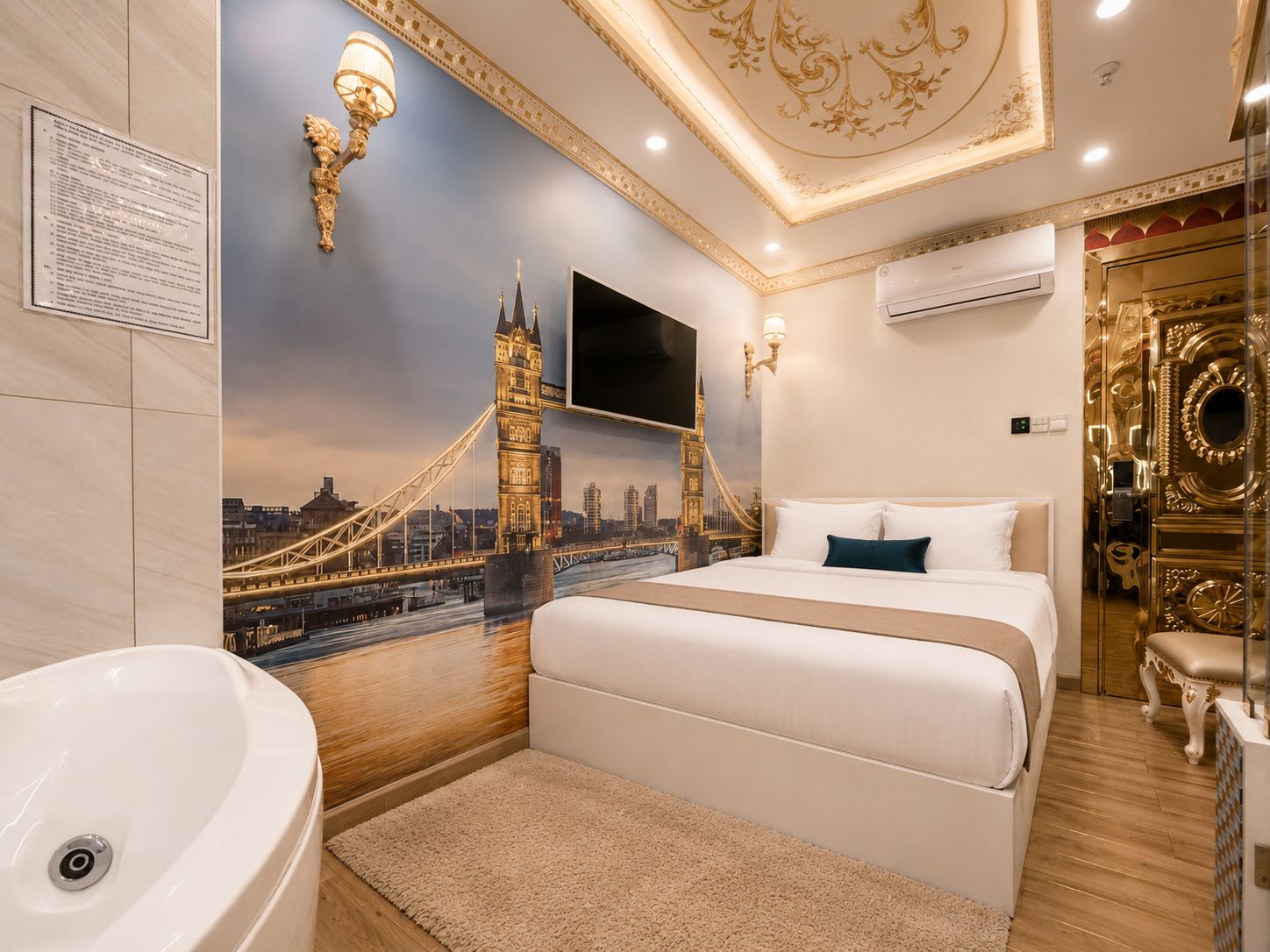 Habitación de hotel con cama, un amplio ventanal con vistas a la ciudad, televisor montado en la pared y baño con lavamanos y espejo.