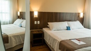 Ein Hotelzimmer mit zwei Betten, Holz-Kopfteilen, Nachttischlampen, einem kleinen Nachttisch und einem Spiegel.