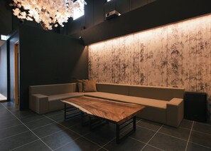 A modern interior with a sofa, a wooden table, and a wall with a bamboo pattern. - 4-minute walk from Shibuya Station / Cherry blossoms blooming at the end of your journey / An inn where your heart finds peace in traditional Japanese tranquility (渋谷区)