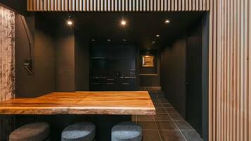 A modern kitchen with a wooden island, bar stools, and a dark interior.