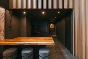 A modern kitchen with a wooden island, bar stools, and a dark interior.