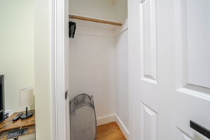 A room with a wooden floor, a white door, a desk with a lamp, and a chair.