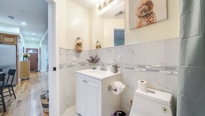 Une salle de bain moderne avec un meuble-lavabo blanc, un miroir, des toilettes et un espace douche.