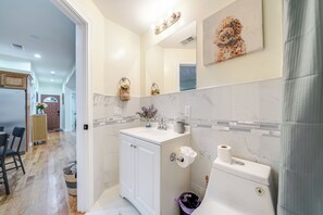 Een moderne badkamer met een witte wastafel, een spiegel, een toilet en een douchecabine.