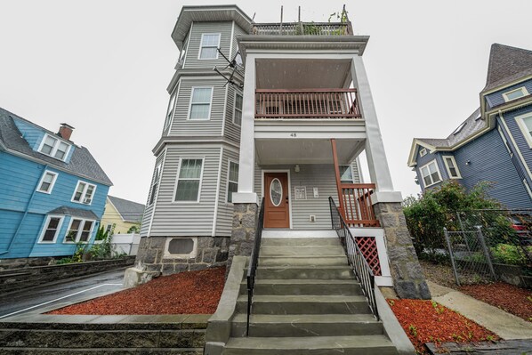 A two-story house with a front porch and a staircase leading to the entrance.