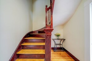 A wooden staircase with a handrail and a small table with flowers beside it.