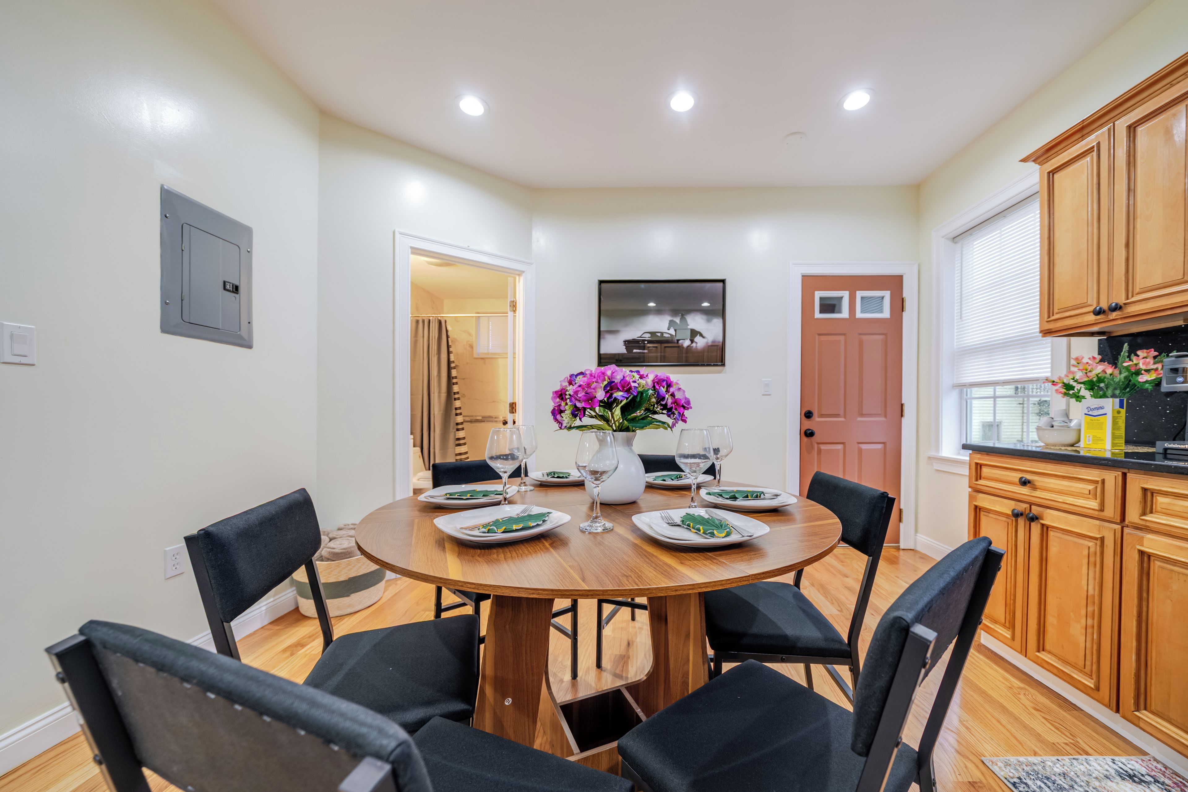 Une salle à manger avec une table ronde, six chaises et un vase de fleurs.
