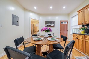 A dining room with a round table, six chairs, and a vase of flowers.