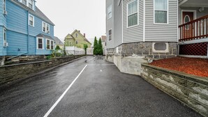 A residential street with houses on both sides, a clear road, and a stone wall on one side.