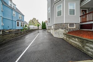 A residential street with houses on both sides, a clear road, and a stone wall on one side.