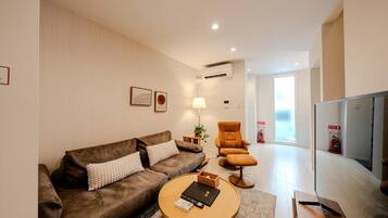 A modern living room with a brown sofa, a round coffee table, and a television.