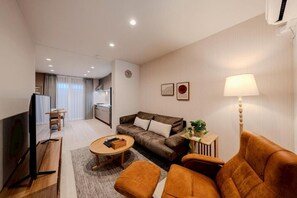 A modern living room with a sofa, ottoman, coffee table, and a television. - NIKYO Sora Inn II Private Villa OSAKA (Osaka)