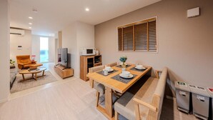 A modern living room with a sofa, coffee table, and a dining area with a table and chairs. - NIKYO Sora Inn II Private Villa OSAKA (Osaka)