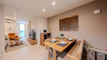 A modern living room with a sofa, coffee table, and a dining area with a table and chairs.