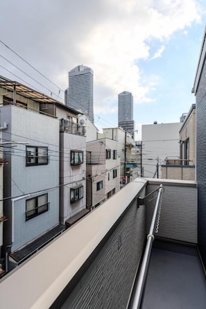 A residential building with multiple floors, balconies, and a view of taller buildings in the background. - NIKYO Sora Inn II Private Villa OSAKA (Osaka)
