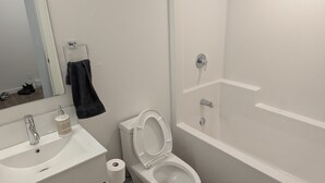 Ett badrum med ett vitt handfat, en toalett och ett badkar.