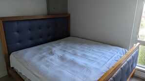 A single bed with a wooden frame and a dark headboard in a room with a window. - Island Retreat - Relax and Explore (Victoria)