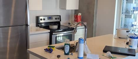 Una cocina moderna con una isla central, electrodomésticos de acero inoxidable y un ventanal que proporciona luz natural.