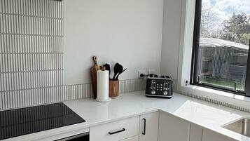 Eine moderne Küche mit weißen Schränken, einem schwarzen Herd und einem Fenster mit Blick ins Freie.