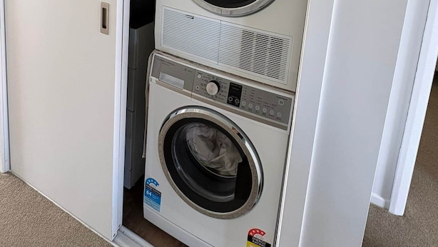 Pequeña lavandería blanca con dos puertas, que incluye lavadora y secadora integradas.