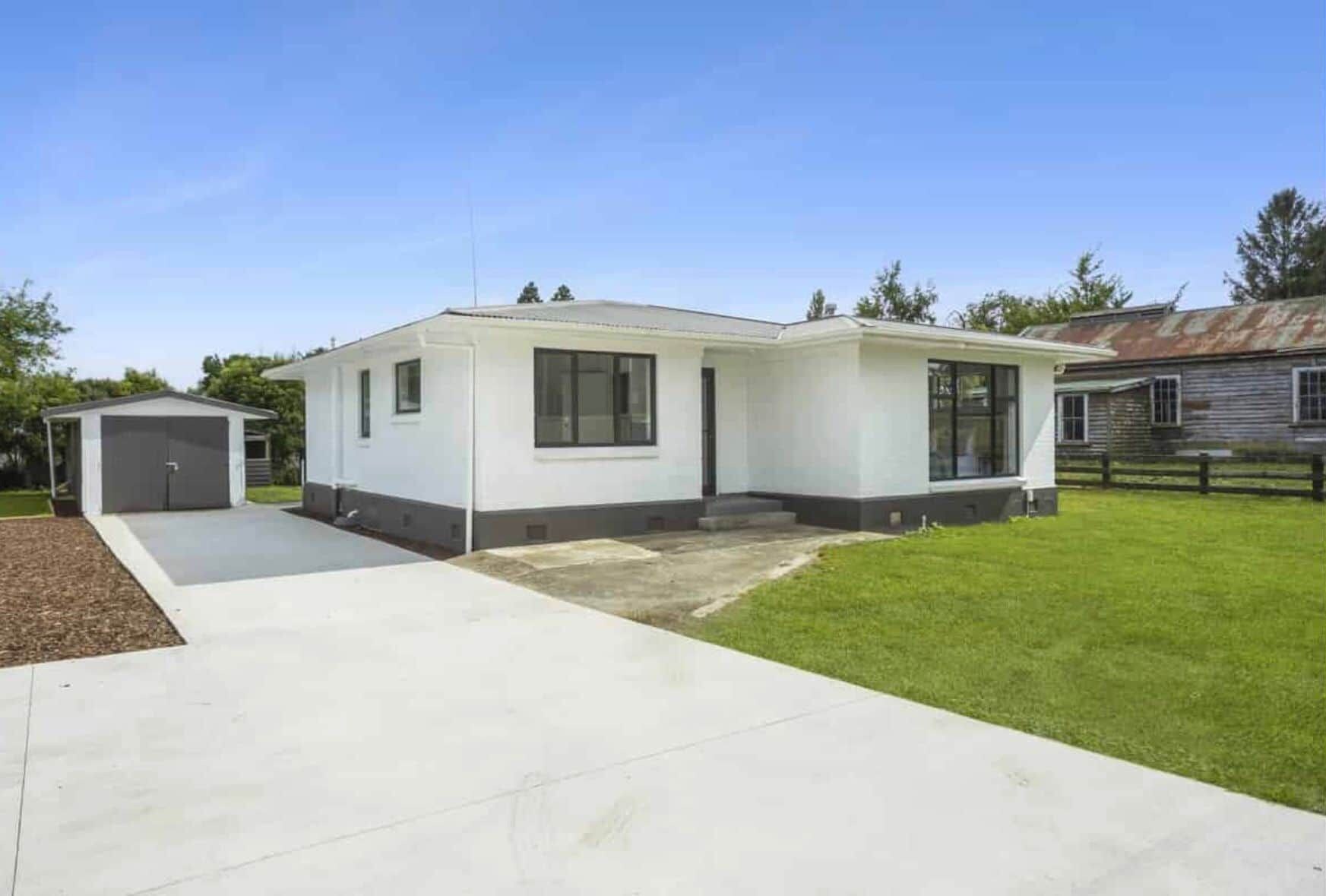 Einbungalow mit Garage, überdachter Terrasse und gepflegtem Rasen.