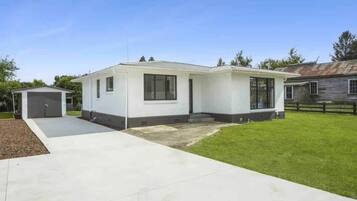 Einbungalow mit Garage, überdachter Terrasse und gepflegtem Rasen.