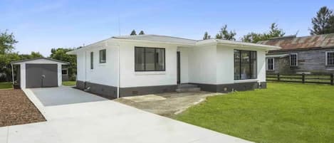 A single-story house with a garage, a covered patio, and a well-maintained lawn.