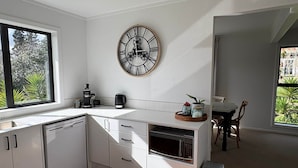 Una cocina moderna con armarios blancos, horno empotrado y un gran reloj de pared.