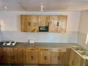 Una cocina con armarios de madera, microondas, estufa y lavaplatos.