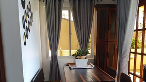 A dining area with a wooden table and benches, a potted plant, and a window with curtains. - Noah Bed&Breakfast 3 Private Room NEWHOMEQuiet Place SINGLE ROOM SHARED BATHROOM (Puerto Princesa City)