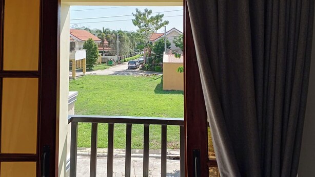 A view from a balcony with a railing, a grassy area, and buildings in the background. - Noah Bed&Breakfast 3 Private Room NEWHOMEQuiet Place SINGLE ROOM SHARED BATHROOM (Puerto Princesa City)
