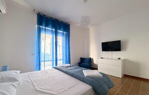 A bedroom with a bed, a dresser, a television, and a window with curtains. - Gorgeous home in Arenella with house sea view (Arenella)