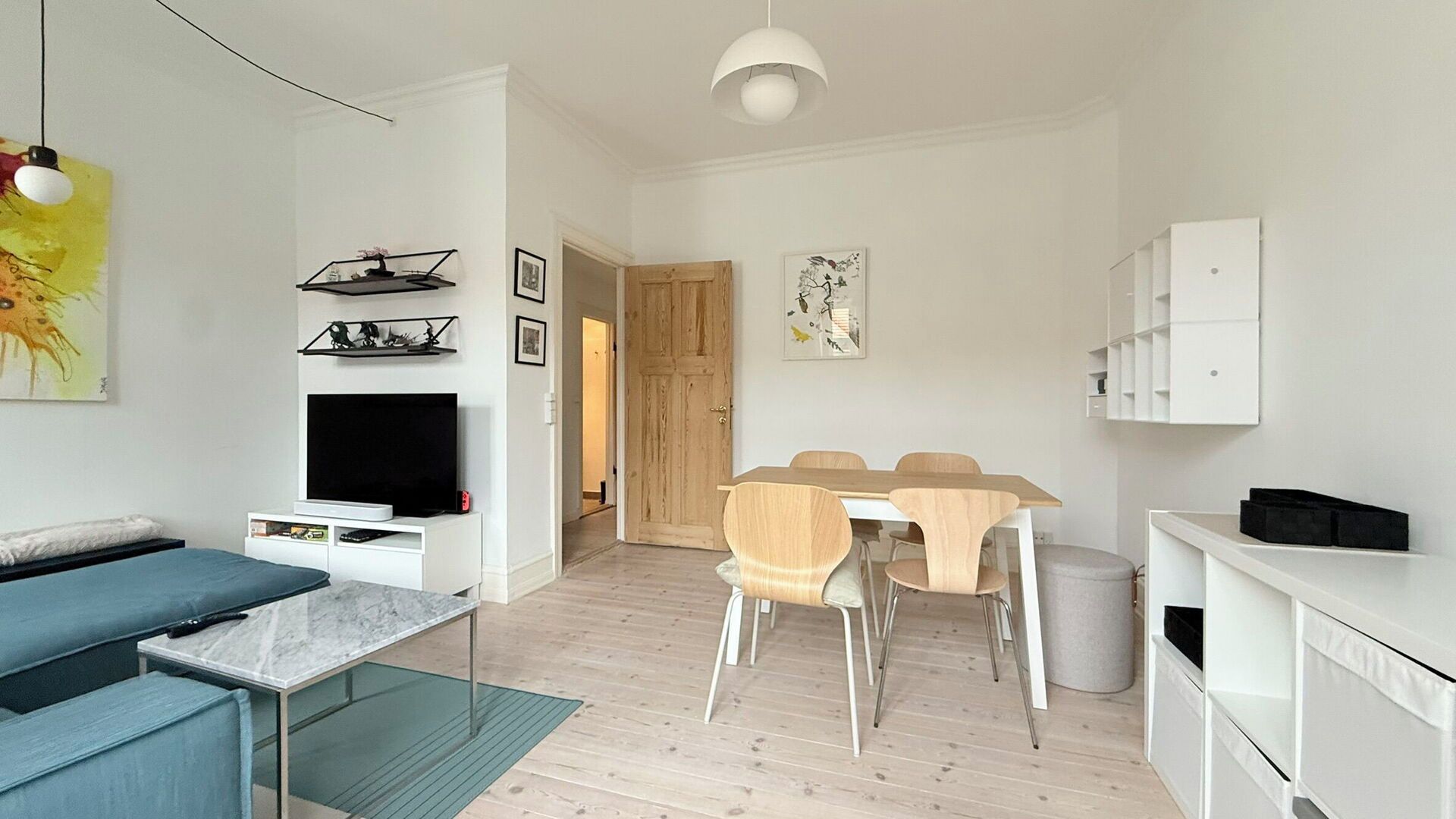 A modern living room with a sofa, TV, and artwork on the wall.