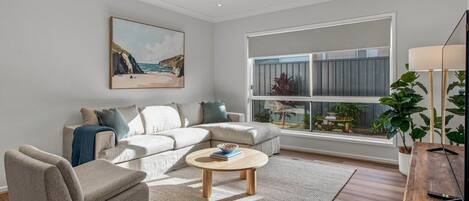 A modern living room with a sectional sofa, a coffee table, and a large window with a view of the outdoors.