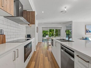 A modern kitchen with white cabinetry, stainless steel appliances, and a wooden floor.