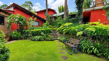 A red brick house with a well-maintained garden, a wooden bench, and a stone staircase leading to the entrance.